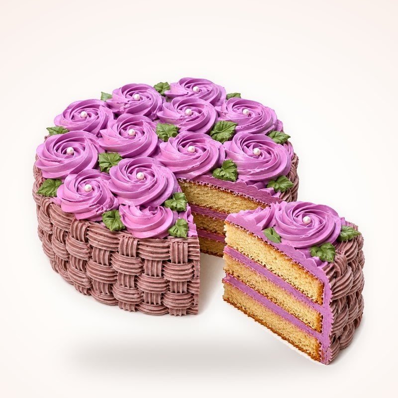 Torta con rosetones lilas y tejido de canasta, con una porción de bizcocho de vainilla